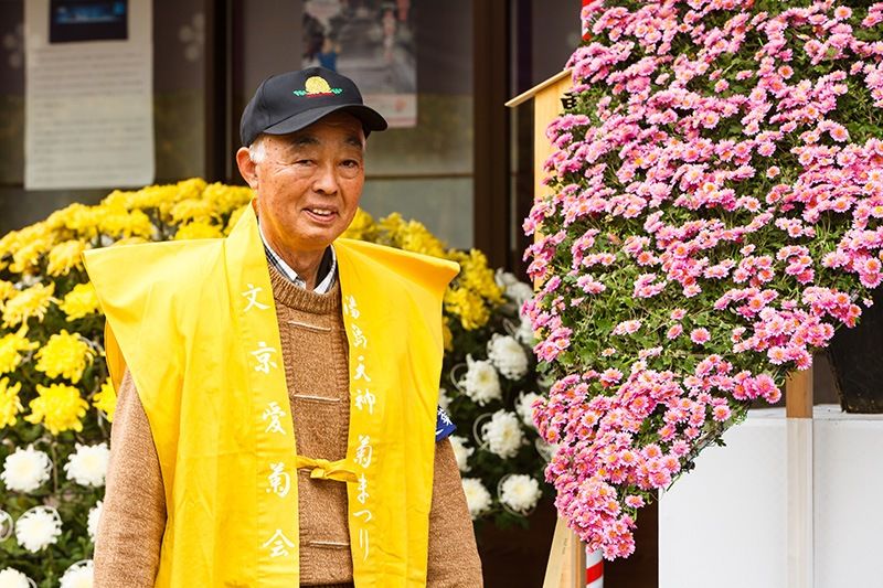 Сугімото Кейдзі, голова Товариства любителів хризантем району Бункё з одним зі своїх творів - каскадом рожевих хризантем
